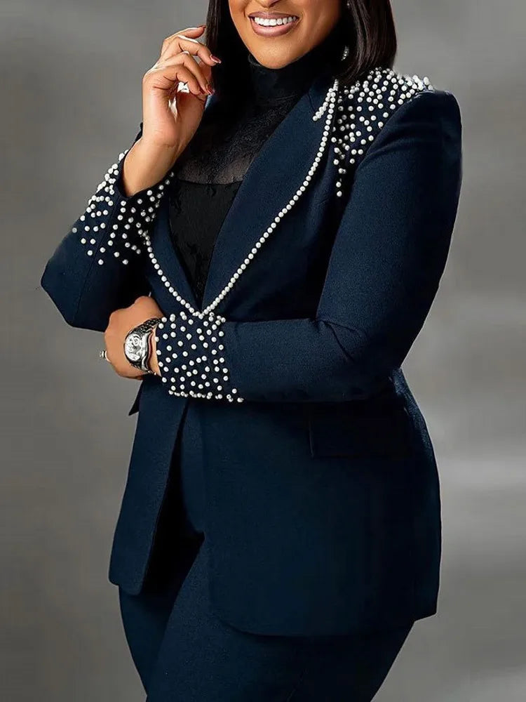 Giacca elegante blu scuro con perle decorative su spalle e polsini, indossata da donna. Moda formale, abbigliamento da ufficio, stile sofisticato.