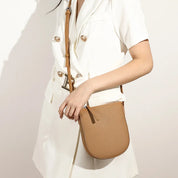 Donna con borsa a tracolla beige in pelle, abito bianco elegante. Accessorio moda femminile, stile casual chic, perfetto per ogni occasione.