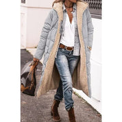 Cappotto lungo imbottito grigio con interno in pelliccia sintetica, indossato con jeans e stivali marroni. Look casual autunnale. Moda donna inverno.