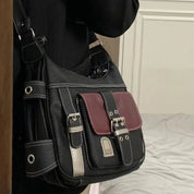 Borsa a tracolla nera con dettagli in metallo e tasca frontale bordeaux, design elegante e moderno, perfetta per moda urbana e casual.