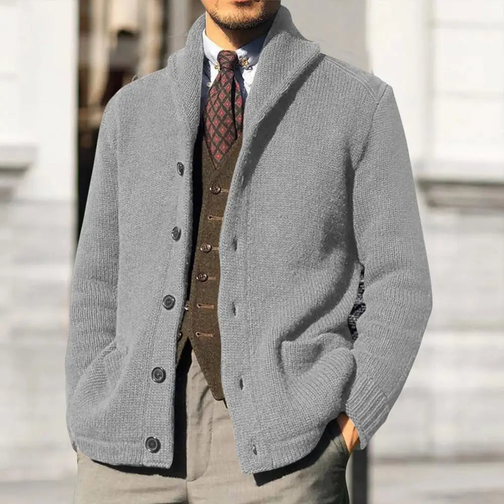 Giacca cardigan uomo grigia in maglia, con bottoni, indossata su camicia bianca e gilet marrone. Elegante e casual per l'autunno.