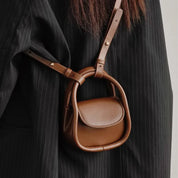 Borsa a tracolla in pelle marrone su cappotto nero a righe. Design elegante e moderno, accessorio moda donna, stile autunno inverno.