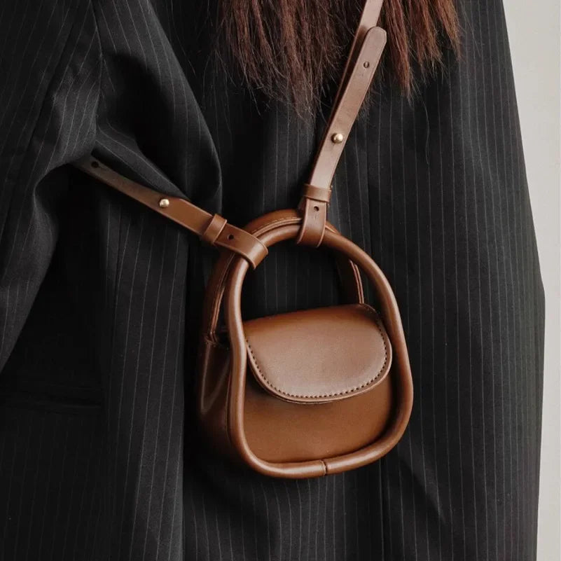 Borsa a tracolla in pelle marrone su cappotto nero a righe. Design elegante e moderno, accessorio moda donna, stile autunno inverno.
