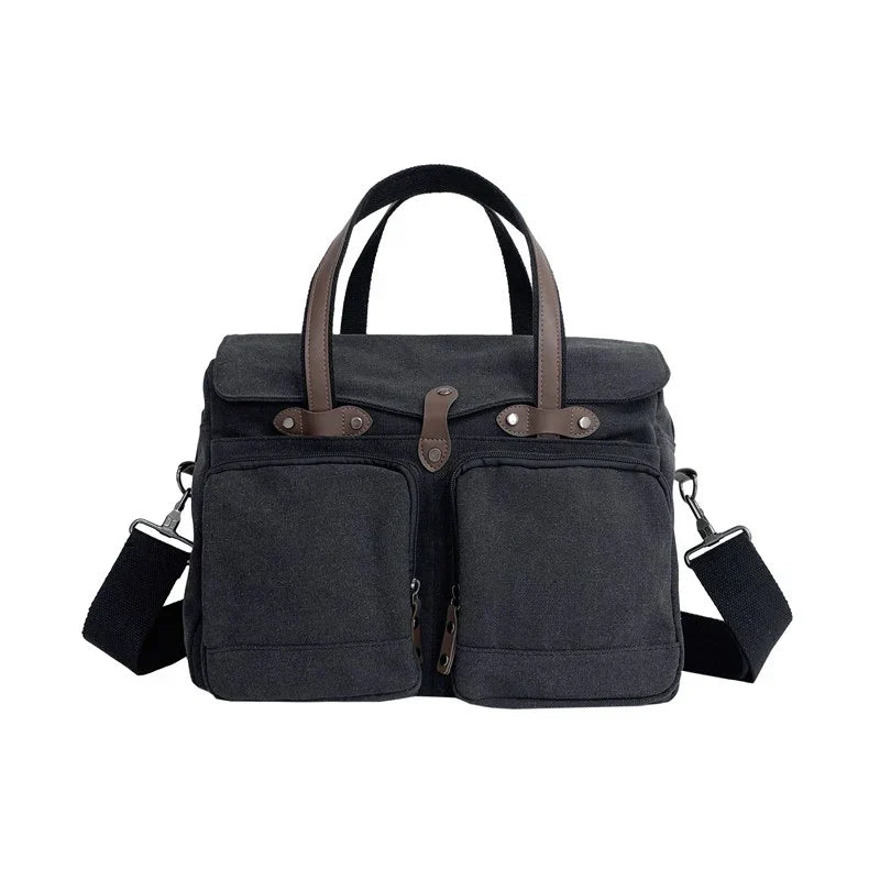 Borsa a tracolla in tela nera con manici marroni, doppie tasche frontali e tracolla regolabile. Design elegante e funzionale per uomo e donna.