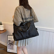 Donna con borsa a tracolla nera, indossa maglietta oversize e gonna plissettata. Stile casual, moda urbana, accessori femminili.