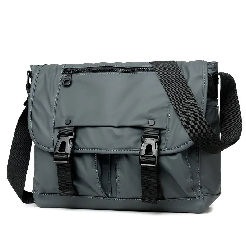 Borsa a tracolla grigia unisex, design moderno, con chiusure a fibbia e tasca frontale con zip. Ideale per lavoro e viaggio.
