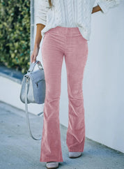 Pantaloni a zampa rosa in velluto, abbinati a maglione bianco lavorato a maglia. Donna con borsa grigia, moda autunnale casual chic.