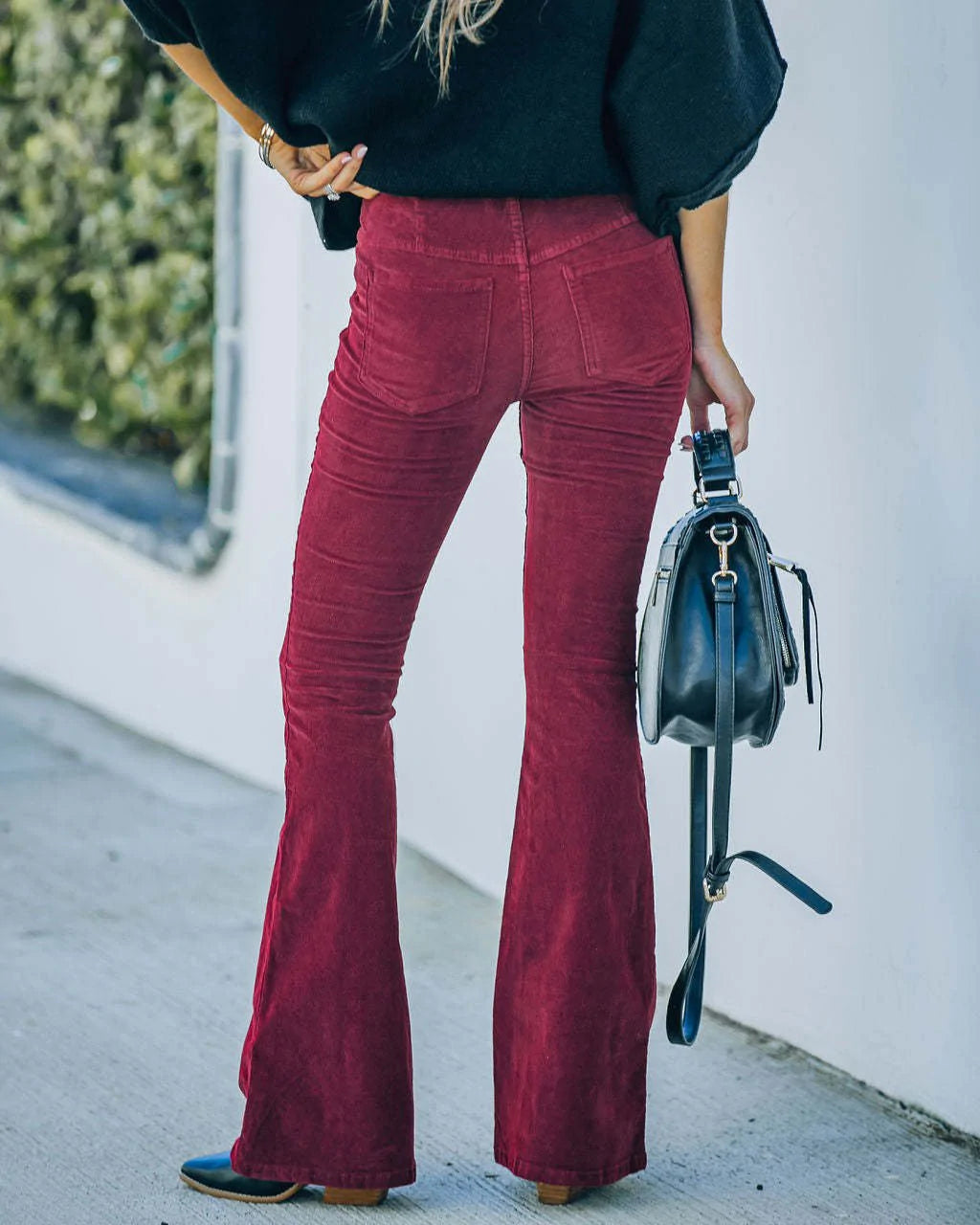 Donna con pantaloni a zampa rossi e borsa nera, moda autunnale, abbigliamento casual elegante, tendenze moda 2023, look street style.