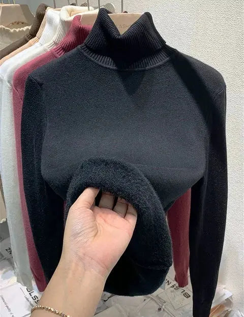Maglione nero a collo alto in lana, esposto su appendiabiti con altri colori. Moda invernale, abbigliamento caldo e confortevole.