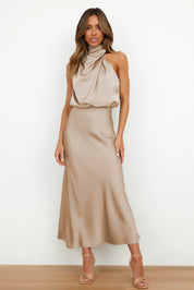 Abito lungo elegante in raso beige, senza maniche, con scollo drappeggiato. Perfetto per eventi formali e serate speciali.
