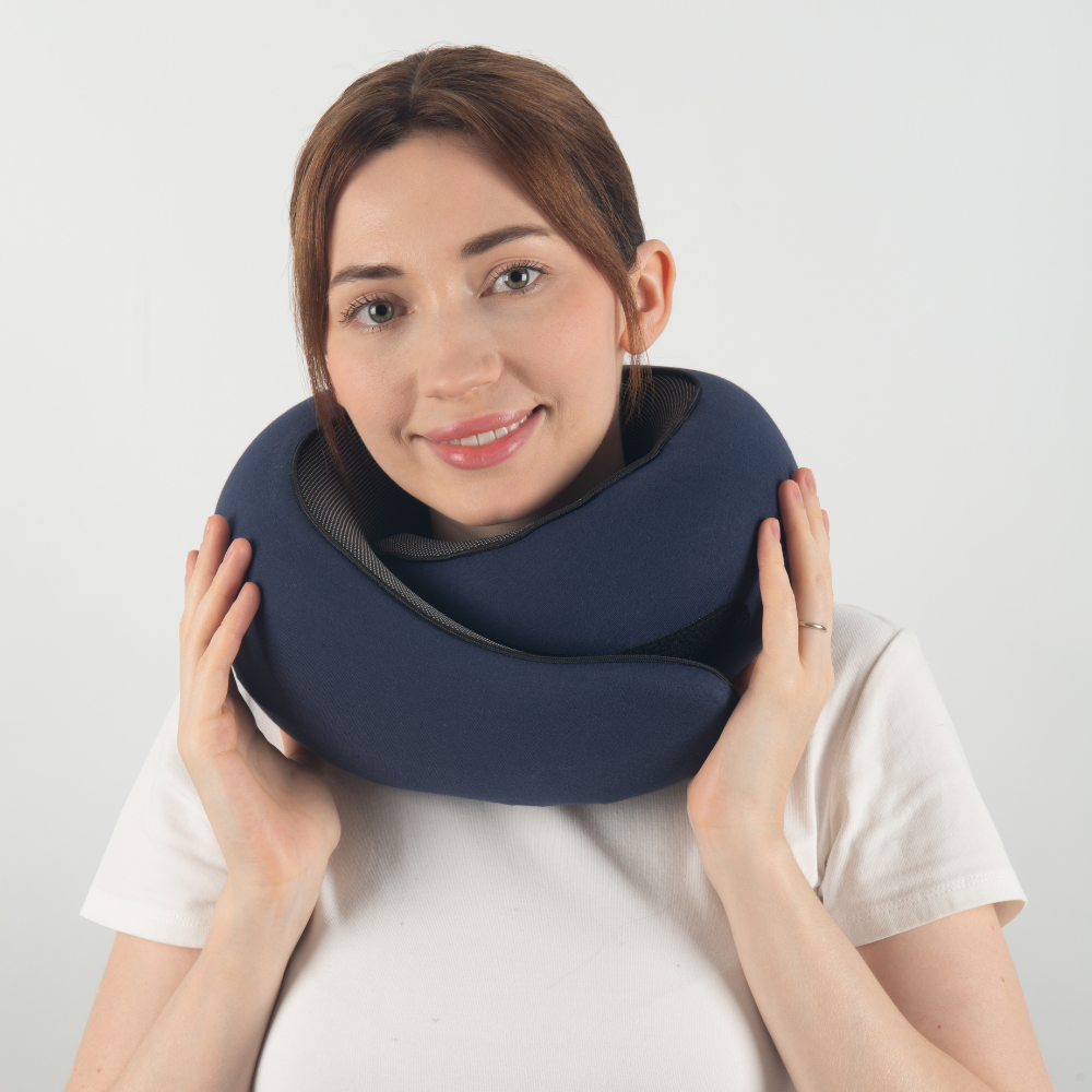 Donna con cuscino da viaggio ergonomico blu, supporto collo, comfort viaggio, accessorio essenziale per aereo, treno, auto, relax e riposo.