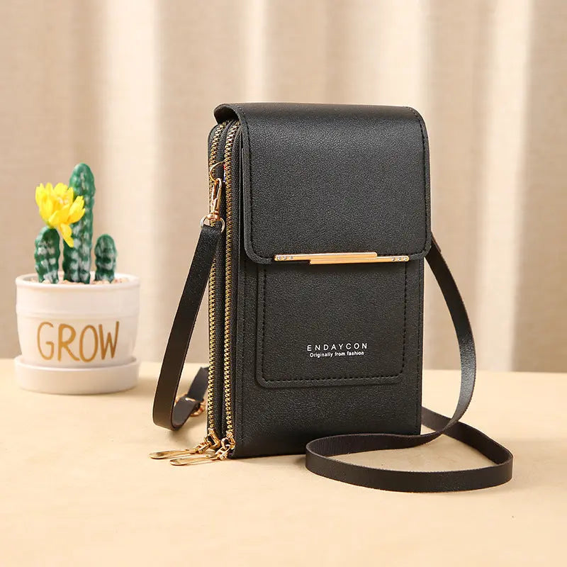 Borsa a tracolla nera in pelle PU con cerniera dorata, design compatto, accanto a vaso con cactus. Elegante accessorio moda donna.