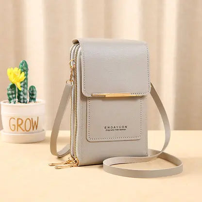 Borsa a tracolla in pelle grigia con tasca frontale, chiusura a zip e dettagli dorati. Design elegante e compatto, ideale per smartphone e accessori.