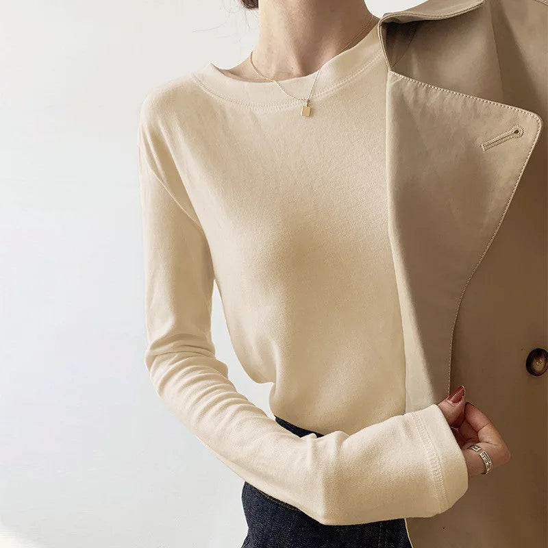 Maglia beige a maniche lunghe da donna, abbinata a cappotto beige. Stile casual ed elegante, ideale per moda autunnale.
