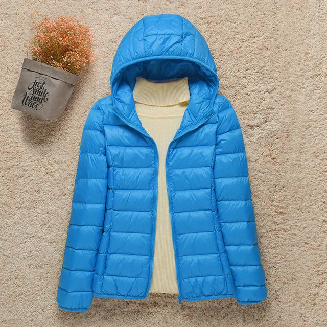 Giacca invernale blu con cappuccio, imbottita, su sfondo beige. Perfetta per il freddo, moda donna, abbigliamento casual.