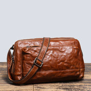 Borsa a tracolla in pelle marrone, design elegante e vintage, con cerniera e tasche multiple. Accessorio moda uomo, ideale per lavoro e viaggio.
