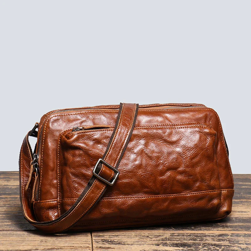 Borsa a tracolla in pelle marrone, design elegante e vintage, con cerniera e tasche multiple. Accessorio moda uomo, ideale per lavoro e viaggio.