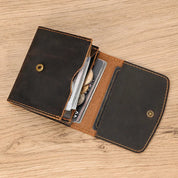 Portafoglio in pelle marrone aperto su tavolo di legno, con scomparti per carte di credito e monete. Accessorio elegante e funzionale per uomo e donna.