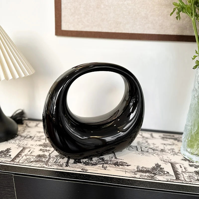 Scultura moderna nera a forma di anello su tavolo decorativo, design elegante per interni, complemento d'arredo contemporaneo, arte astratta.