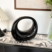 Scultura moderna nera a forma di anello su tavolo decorativo, design elegante per interni, complemento d'arredo contemporaneo, arte astratta.
