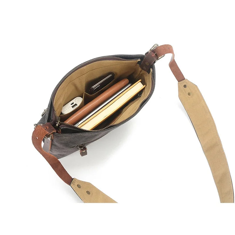 Borsa a tracolla in pelle marrone con scomparti interni, contenente libri, smartphone e accessori. Design elegante e funzionale per uso quotidiano.