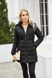 Giacca invernale nera imbottita da donna, con cappuccio, zip frontale, indossata all'aperto. Elegante e calda, ideale per l'inverno.
