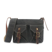 Borsa a tracolla in tela nera con doppie tasche frontali, fibbie in pelle marrone e cinturino regolabile. Stile vintage, ideale per uomo e donna.
