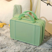 Valigia verde pastello su tappeto grigio, design compatto e moderno, ideale per viaggi brevi. Accessorio da viaggio elegante e funzionale.