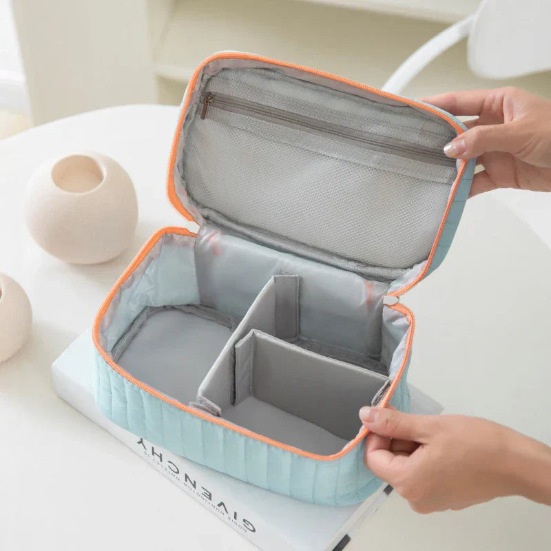 Astuccio da viaggio azzurro con divisori interni regolabili, cerniera superiore, design compatto, ideale per cosmetici e accessori.