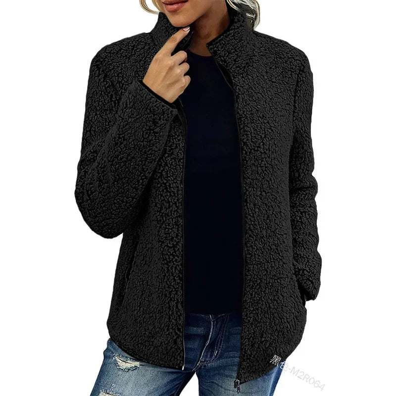 Giacca in pile nero da donna, design casual, chiusura con zip, ideale per l'inverno. Abbinata a jeans strappati per un look moderno e confortevole.