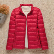 Giacca piumino rosso da donna su sfondo beige, design trapuntato, collo alto, ideale per l'inverno. Moda femminile, abbigliamento caldo.