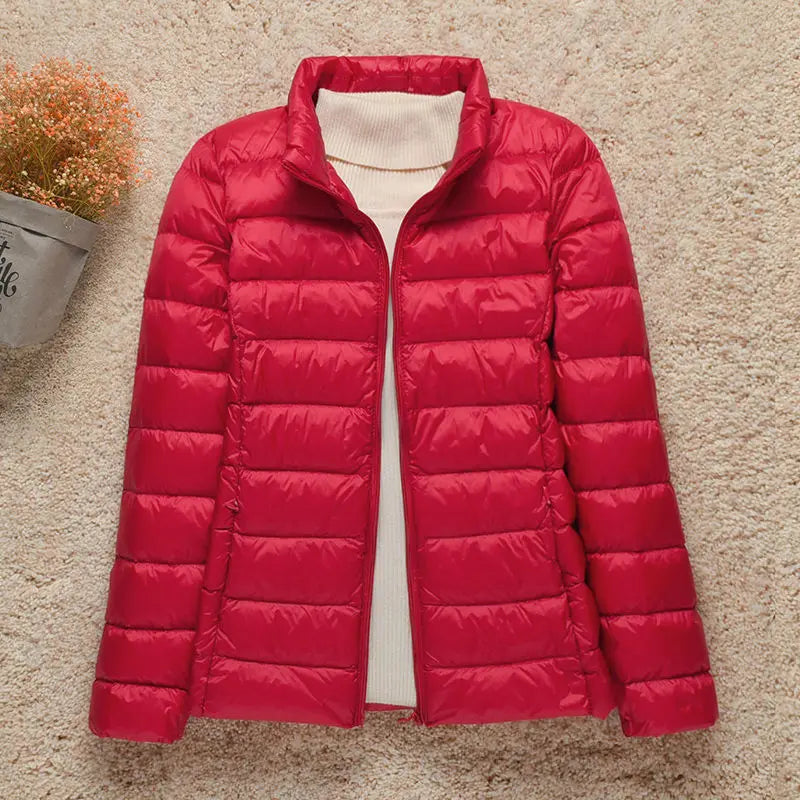 Giacca piumino rosso da donna su sfondo beige, design trapuntato, collo alto, ideale per l'inverno. Moda femminile, abbigliamento caldo.
