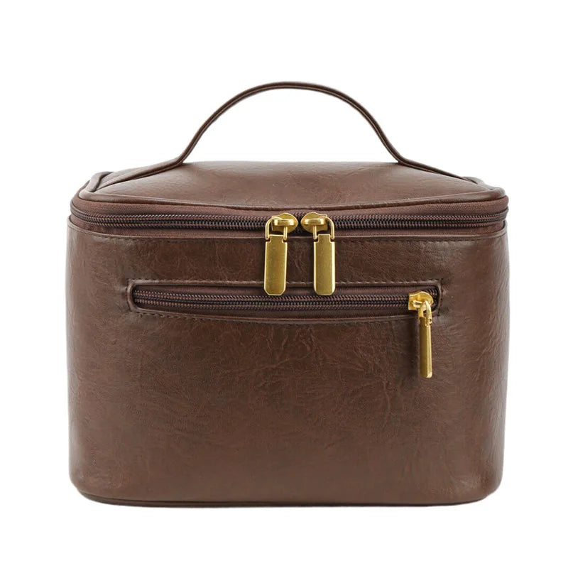 Borsa cosmetica marrone in pelle sintetica con cerniere dorate, manico superiore, tasca frontale. Elegante e pratica per viaggi e organizzazione.