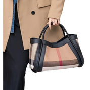 Borsa a mano elegante con motivo a quadri, dettagli in pelle nera, indossata da una persona con cappotto beige. Accessorio moda di tendenza.