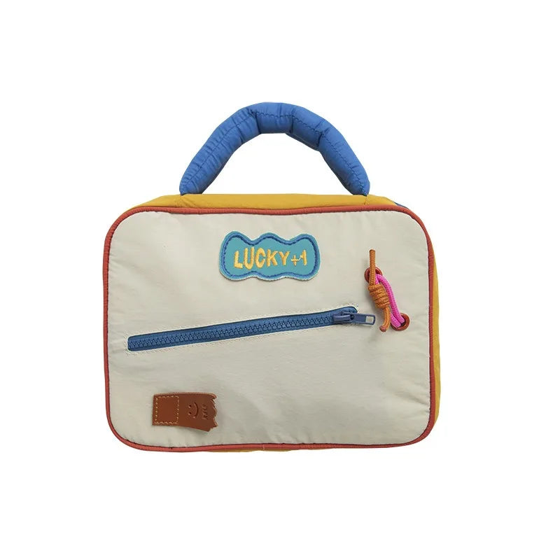 Borsa termica per bambini con manico blu, tasca frontale con cerniera, design colorato e scritta "Lucky+1". Ideale per scuola e picnic.