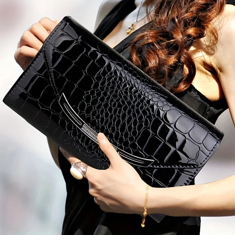 Donna con elegante pochette nera in pelle effetto coccodrillo, abito nero, accessorio moda, borsa da sera, stile sofisticato, tendenza 2023.