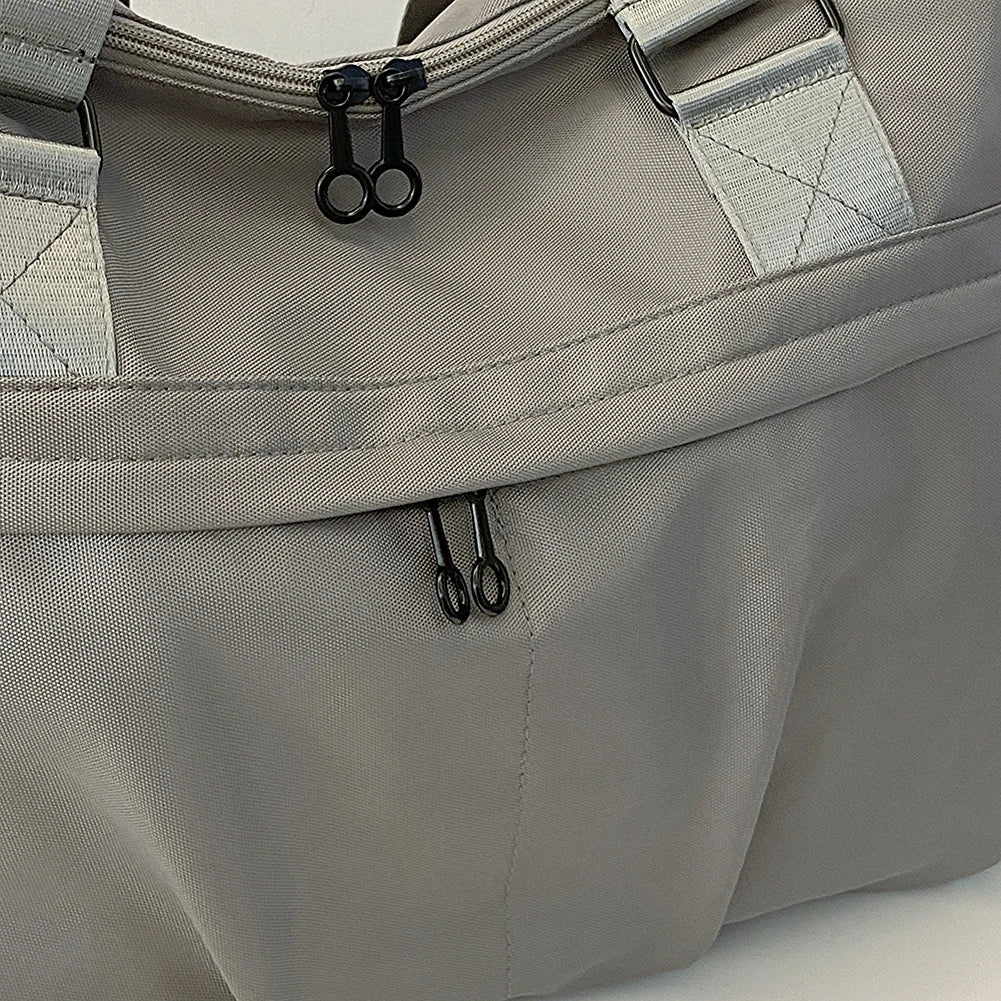 Borsa da viaggio grigia in tessuto resistente con doppia cerniera nera, manici rinforzati. Ideale per viaggi, palestra, weekend.