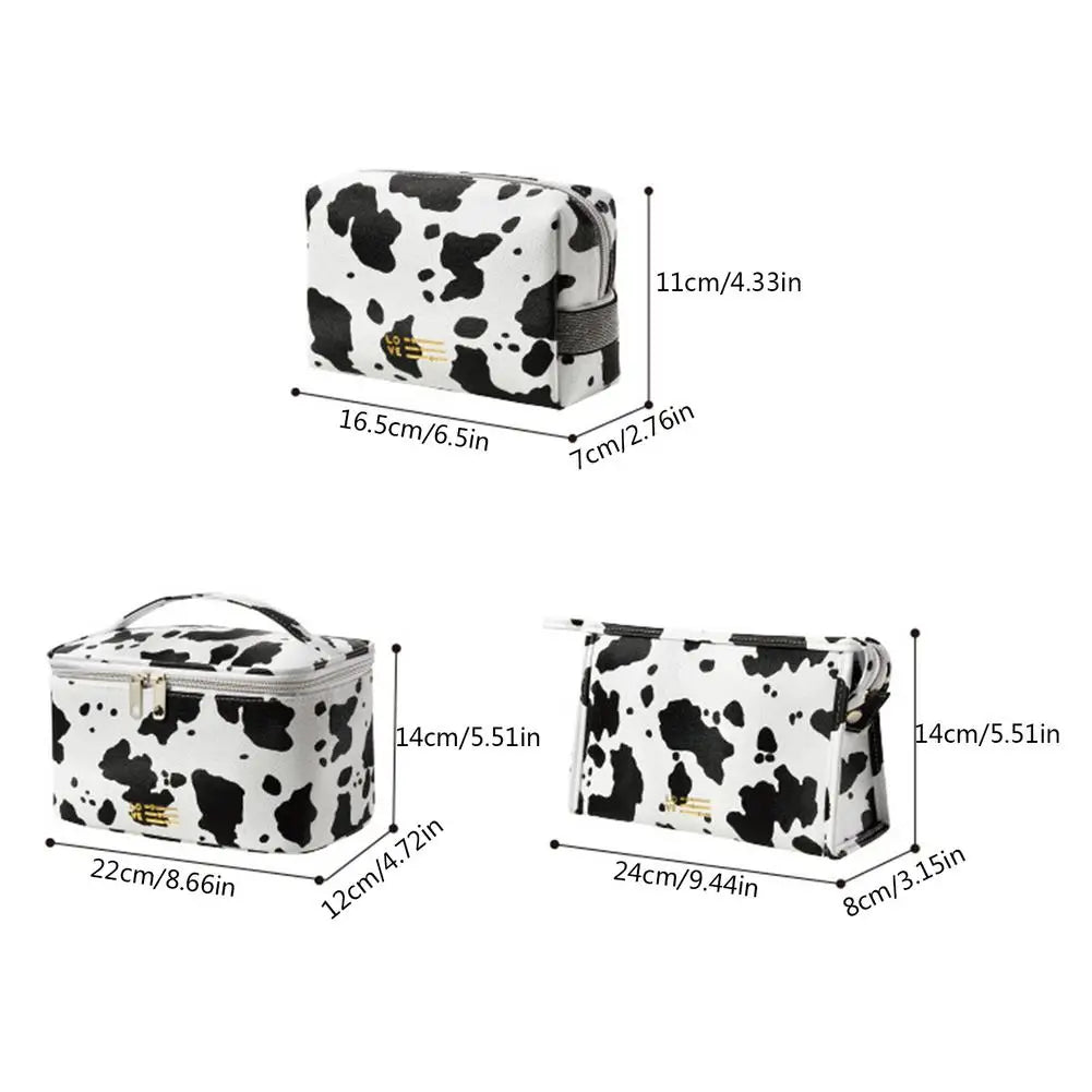 Set di tre beauty case in pelle sintetica con stampa mucca bianco e nero, dimensioni varie, chiusura a zip, ideale per viaggio e organizzazione cosmetici.