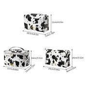 Set di tre beauty case in pelle sintetica con stampa mucca bianco e nero, dimensioni varie, chiusura a zip, ideale per viaggio e organizzazione cosmetici.