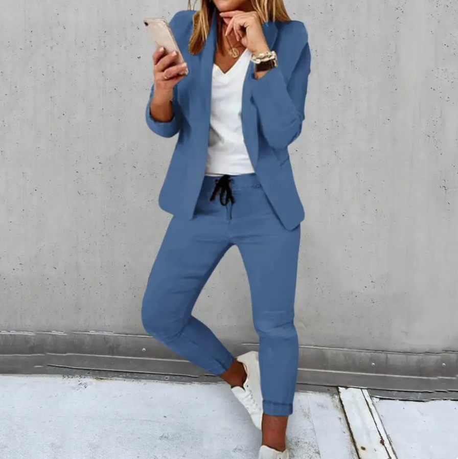 Donna in abito elegante blu, giacca e pantaloni, con smartphone. Moda business casual femminile, abbigliamento da ufficio, stile moderno.