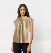 Blusa elegante in raso dorato, senza maniche, con colletto drappeggiato. Indossata da modella su sfondo bianco. Moda donna, abbigliamento chic.
