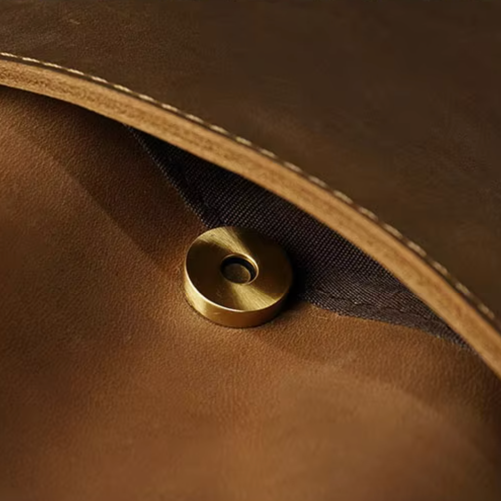 Cerniera magnetica in ottone su borsa in pelle marrone, dettaglio di alta qualità, accessorio moda elegante, chiusura sicura e resistente.