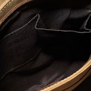 Interno di una borsa in pelle marrone con tasche nere, cerniera aperta. Design elegante, ideale per moda e accessori di lusso.