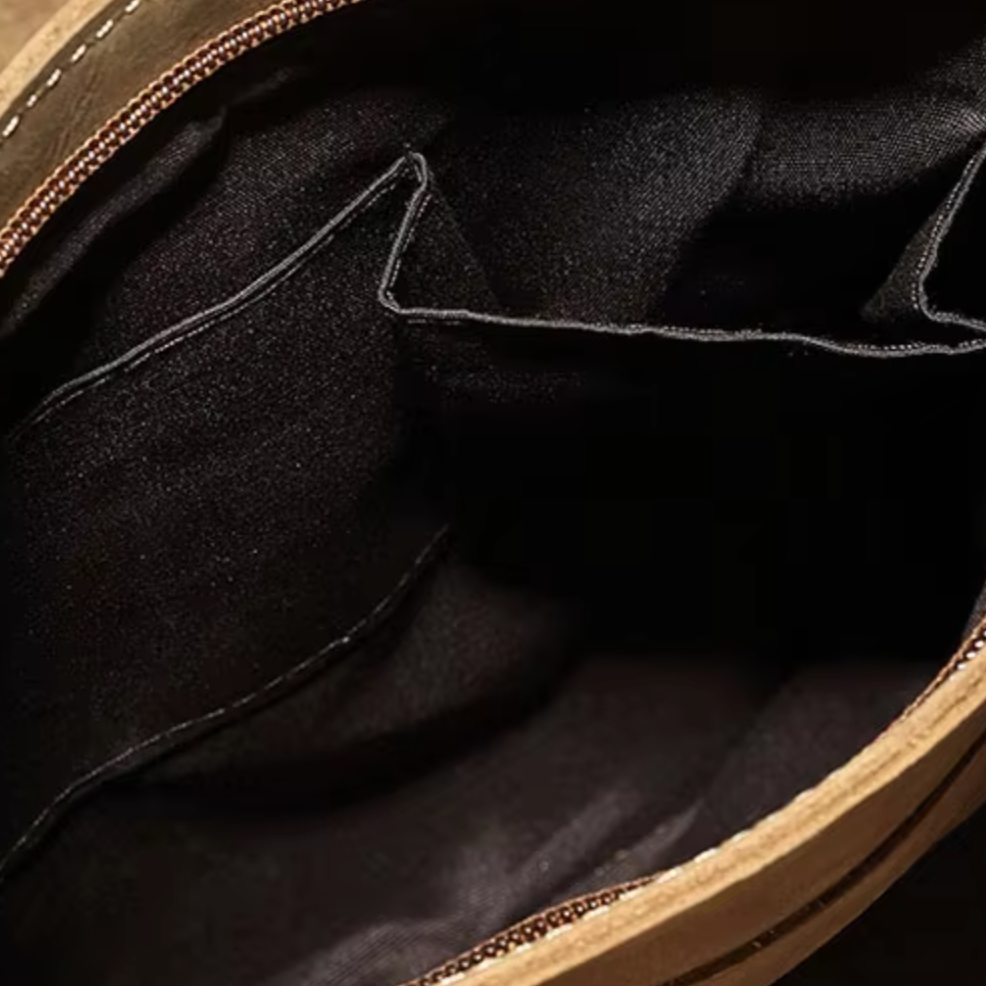 Interno di una borsa in pelle marrone con tasche nere, cerniera aperta. Design elegante, ideale per moda e accessori di lusso.