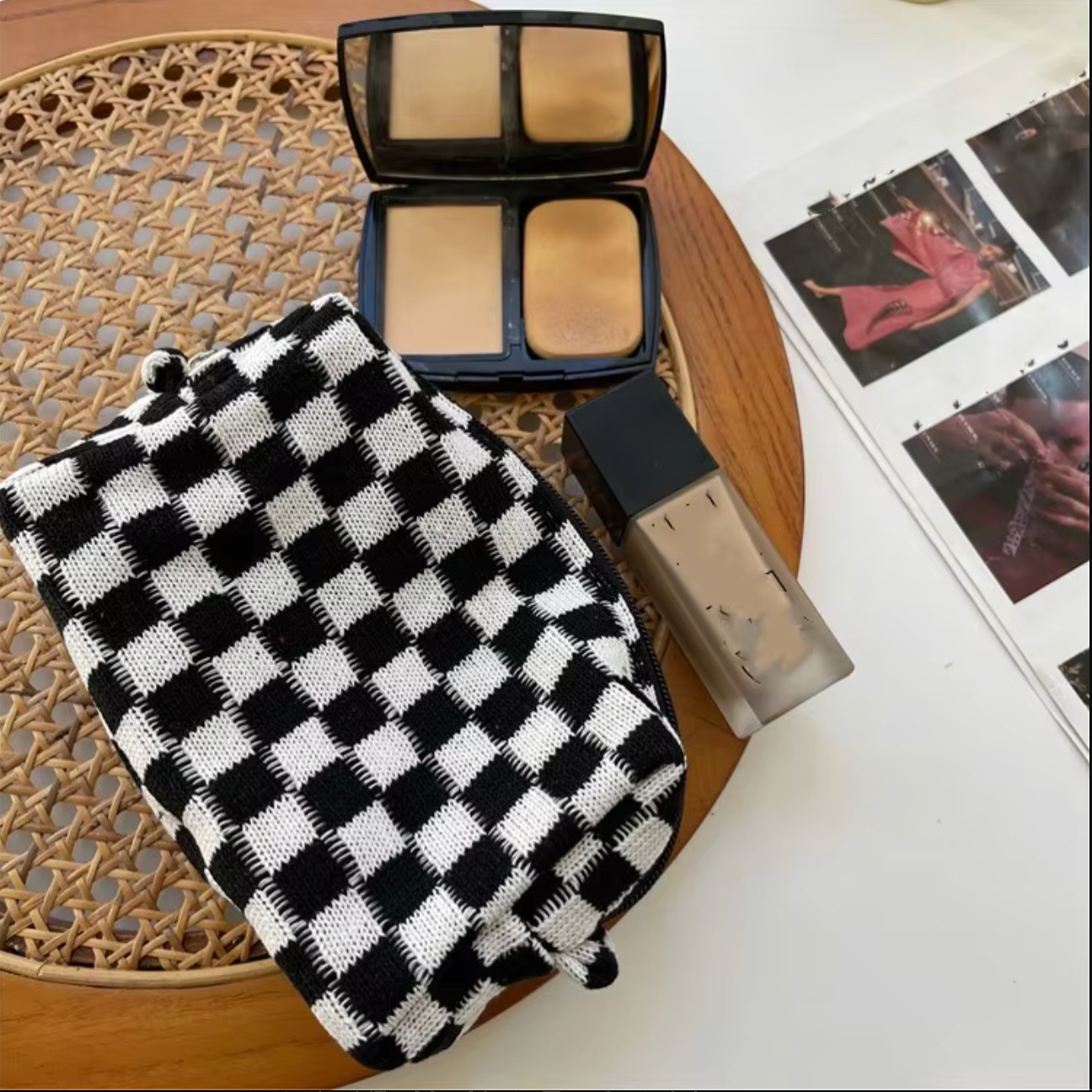 Trucco su tavolo: fondotinta liquido, cipria compatta e fascia a quadri bianchi e neri. Accessori bellezza, cosmetici, moda.