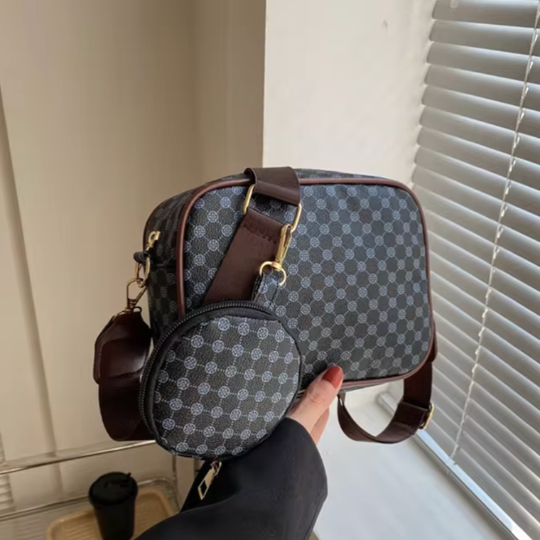 Borsa a tracolla in pelle marrone con motivo geometrico, tasca rotonda aggiuntiva, finestra con persiane sullo sfondo. Accessorio moda elegante.