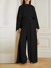 Tuta elegante nera da donna, design moderno con maniche ampie, perfetta per eventi formali. Accessorio borsa dorata. Moda femminile di lusso.