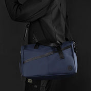 Borsa a tracolla blu scuro, design moderno, tessuto resistente, ideale per viaggi e sport. Uomo in abbigliamento nero. Accessorio versatile ed elegante.