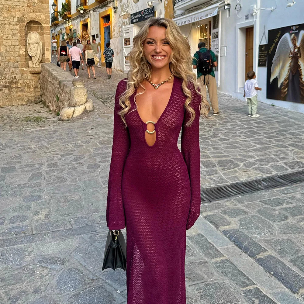 Donna sorridente in abito lungo viola con scollatura profonda, cammina su una strada di ciottoli in un pittoresco borgo italiano.
