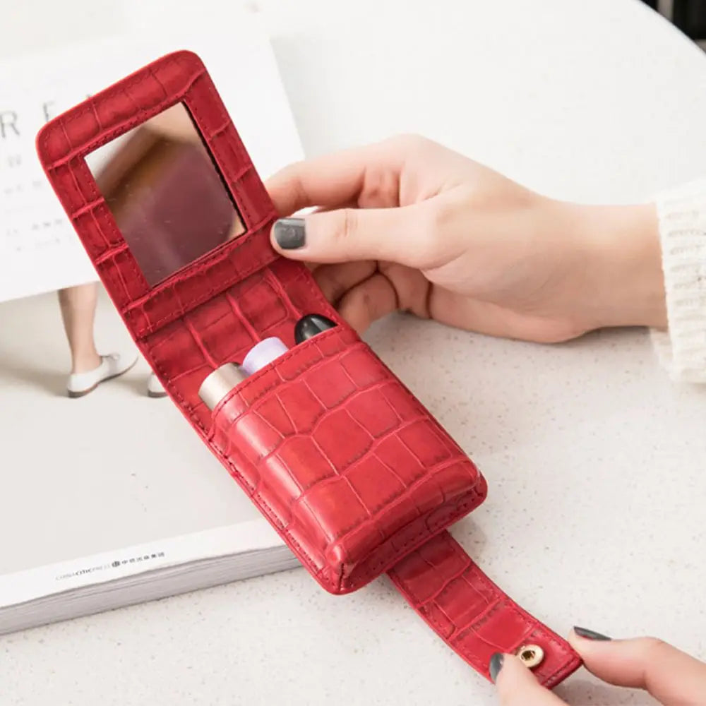 Custodia rossetto rossa in pelle con specchio integrato, design elegante e compatto, ideale per il trucco in viaggio. Accessorio moda donna.